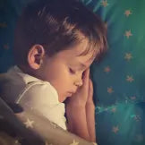 Child with hands over face against a star-patterned blue background