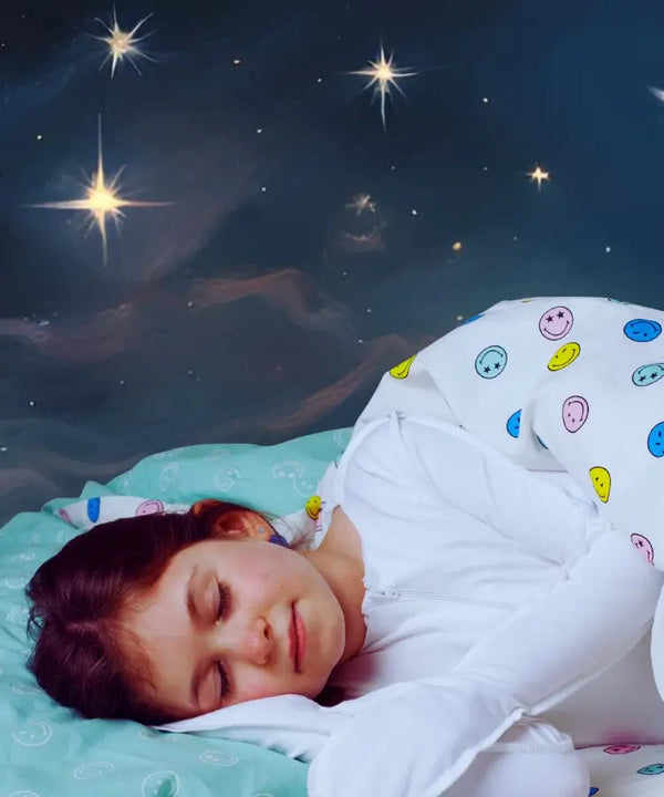 Child sleeping under a starry sky with a colorful pillow and blanket.